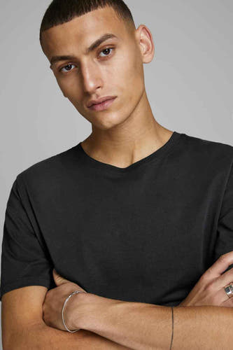 T-shirt noir de CORE BY JACK & JONES, à manches courtes, porté par un modèle avec des bracelets et une bague.