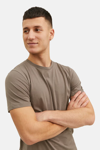 T-shirt brun à manches courtes de CORE BY JACK & JONES, avec des bras croisés et une boucle d'oreille dorée.