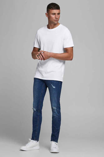 T-shirt blanc de CORE BY JACK & JONES, porté avec un jean bleu déchiré et des baskets blanches.