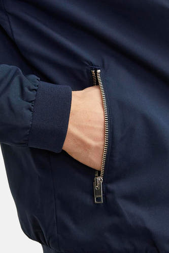 Blauwe korte jas van PREMIUM BLUE by JACK & JONES, met een zilverkleurige rits en een hand in de zak.