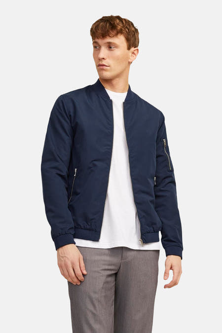 Veste bleue de PREMIUM BLUE par JACK & JONES, portée sur un chemisier blanc et un pantalon gris.