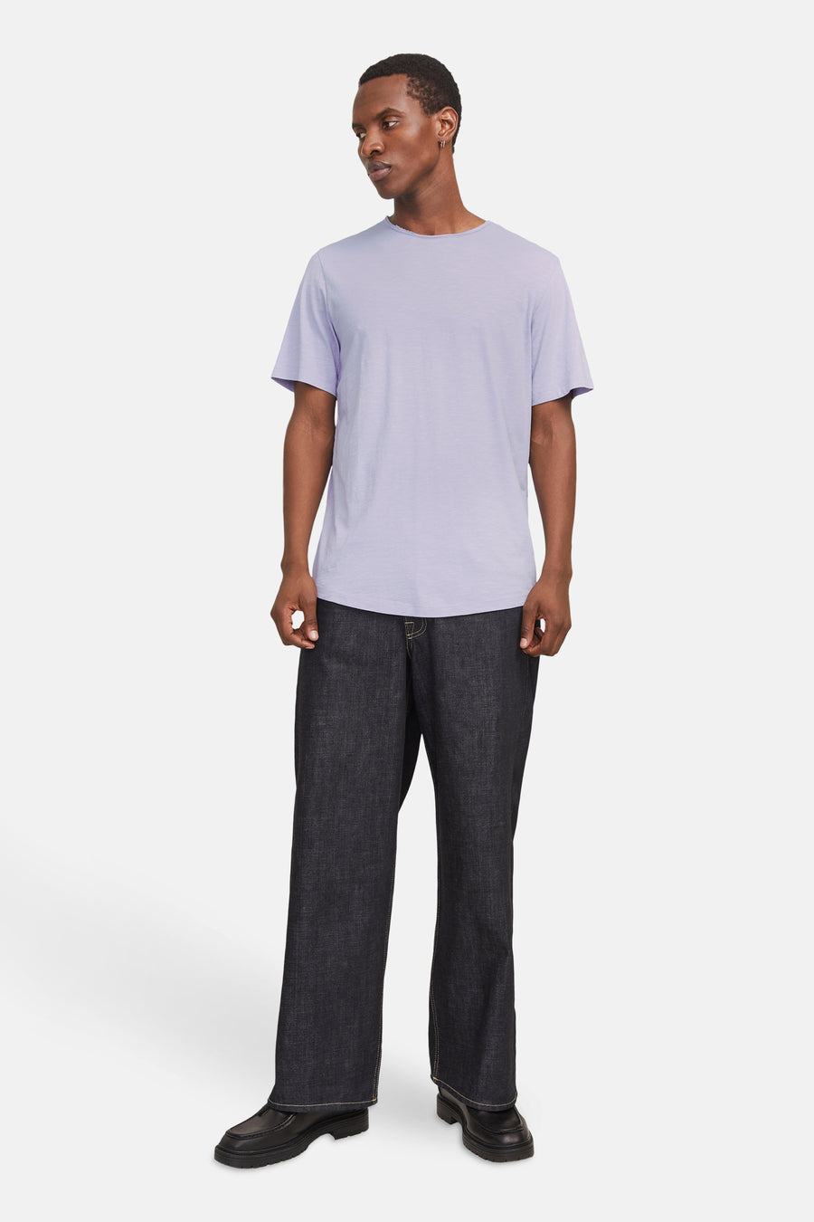 Een man in een lila T-shirt en donkere spijkerbroek.