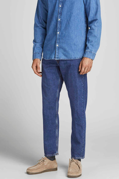 Tapered jeans in middenblauw denim van JACK & JONES JEANS INTELLIGENCE, gecombineerd met een blauw denim overhemd en suède schoenen.