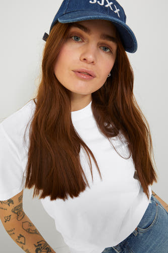 T-shirt blanc de JJXX, porté avec un chapeau de denim bleu et des jeans.