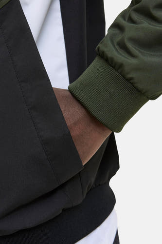 Veste de pluie verte d'ORIGINALS BY JACK & JONES, avec des accents noirs et des bords élastiques, gros plan.