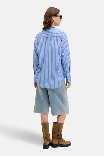 Chemise bleue rayée à manches longues de JJXX, vue de derrière avec des shorts en denim et des bottes brunes.