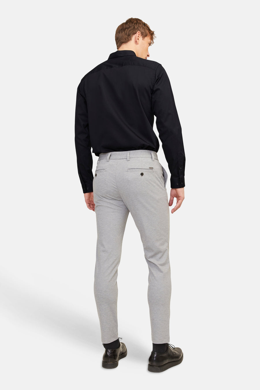 Zwart overhemd (lange mouwen) van PREMIUM by JACK & JONES, achterkant, gecombineerd met grijze pantalon en zwarte schoenen.