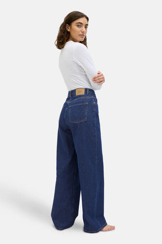 Donkerblauwe wijde jeans van JJXX, met achterzakken en een lichtbruin merklabel, gecombineerd met een wit shirt.