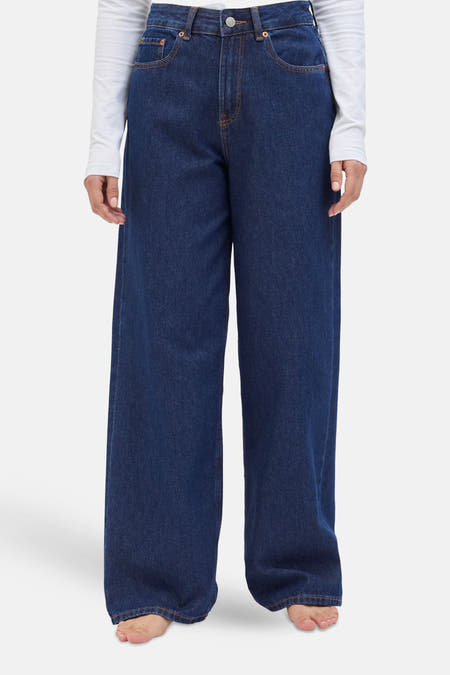 Donkerblauwe denim wide jeans van JJXX, met een lange wijde pijp en een witte top.
