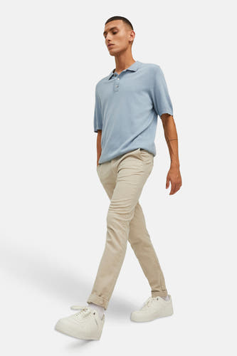 Beige chino van JACK & JONES JEANS INTELLIGENCE, gecombineerd met een lichtblauw poloshirt en witte sneakers.
