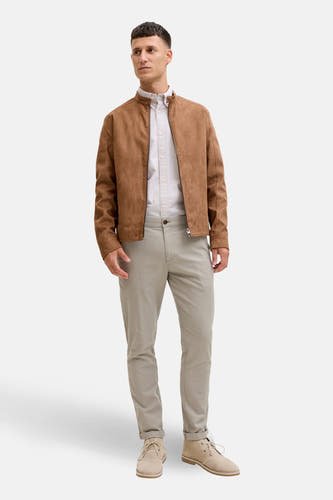 Groene chino van JACK & JONES JEANS INTELLIGENCE, gedragen met een bruine jas en lichte schoenen.
