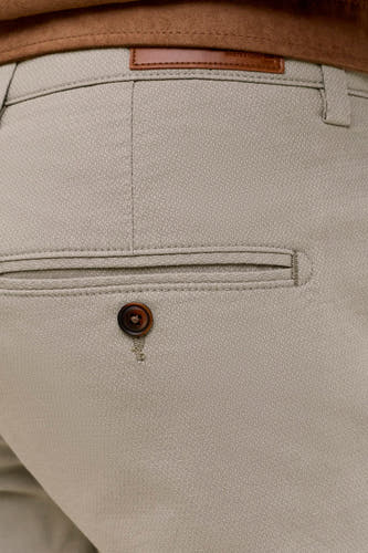 Groene chino van JACK & JONES JEANS INTELLIGENCE, close-up van achterkant met bruine knoop en paspelzak.