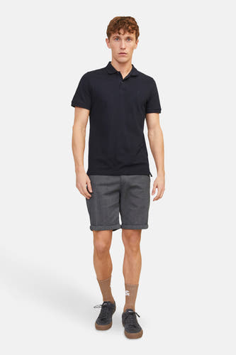 Grijze denim short van JACK & JONES JEANS INTELLIGENCE, met omgeslagen pijpen en gedragen met een donkerblauw poloshirt, sokken en sneakers.
