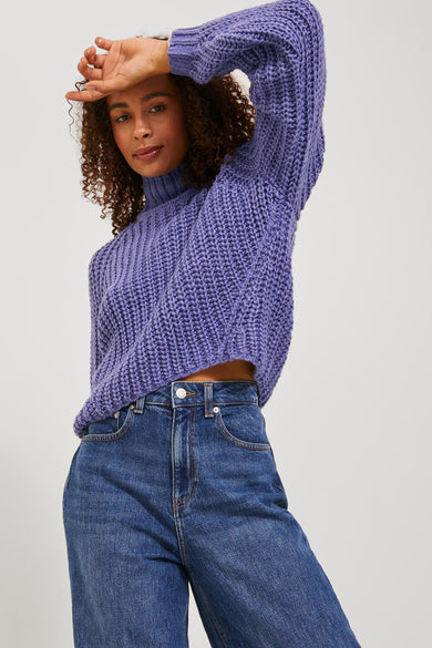 Pull-over marron avec col montant de JJXX, porté avec des jeans bleus et une main sur le front.