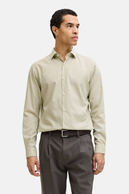 Chemise verte à manches longues de PREMIUM by JACK & JONES, avec une coupe cintrée et portée avec un pantalon gris et des chaussures noires.