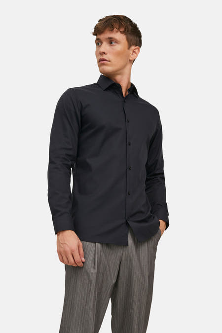 Chemise noire à manches longues de PREMIUM by JACK & JONES, portée avec un pantalon gris à rayures de craie.