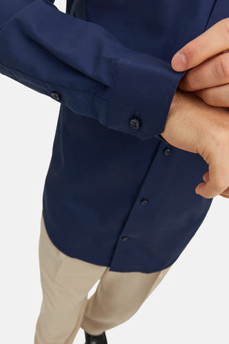 Blauw overhemd met lange mouwen van PREMIUM by JACK & JONES, close-up met geknoopte manchetten en beige pantalon.
