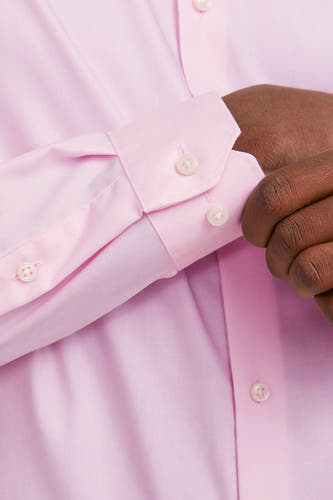 Roze overhemd met lange mouwen van PREMIUM by JACK & JONES, met een man die de knoopjes sluit.
