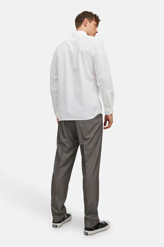 Chemise blanche à manches longues de PREMIUM by JACK & JONES, avec fermeture à boutons, vue de dos, associée à un pantalon gris à rayures et des baskets noires.