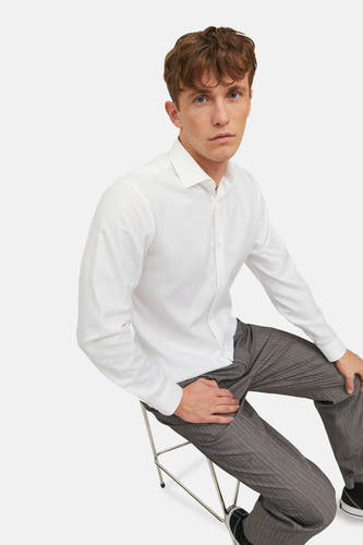 Chemise blanche à manches longues de PREMIUM by JACK & JONES, portée avec un pantalon gris à rayures.