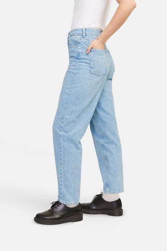 Lichtblauwe mom jeans van JJXX, met hand in de zak en zwarte schoenen.