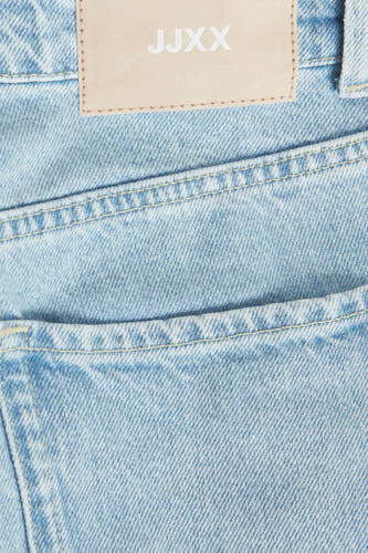Lichtblauwe mom jeans van JJXX, detailopname met zak en merklabel.
