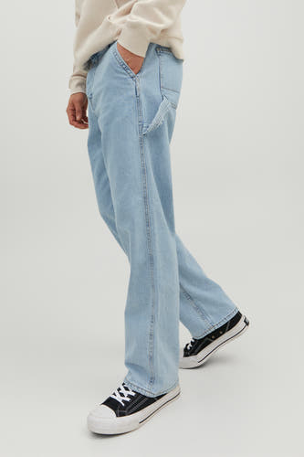 Jean denim bleu clair large de JACK & JONES JEANS INTELLIGENCE, avec une poche à outils, porté avec un pull beige et des baskets noires.