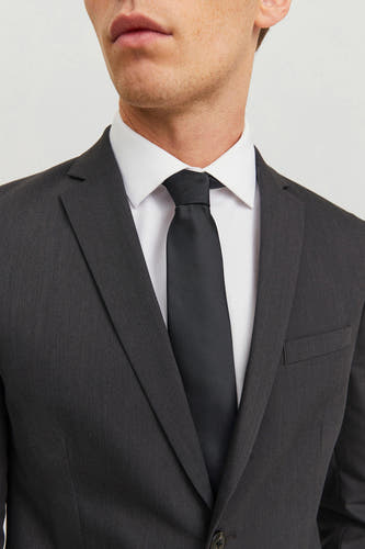 Ceinture noire d'ACCESSORIES BY JACK & JONES, avec un léger brillant et portée avec une chemise blanche et un costume gris.