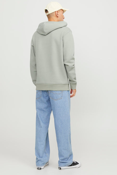 Pull-over vert de capSS BY JACK & & JONES, man longs man combiné avec une casquette beige et des jeans bleus.