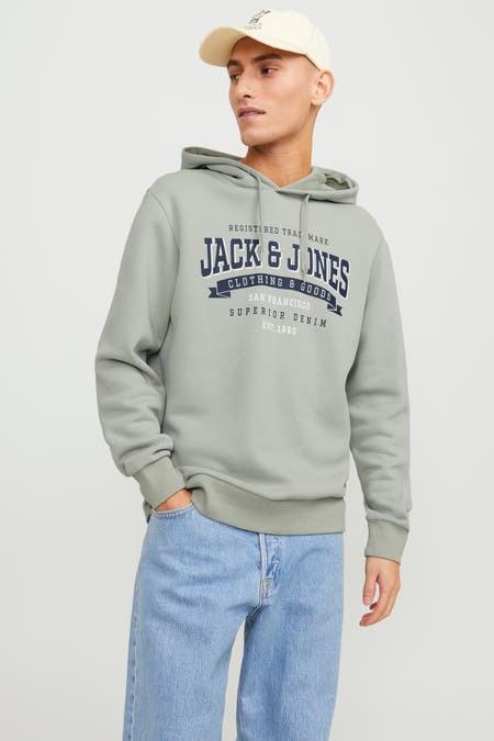 Groene sweater met kap van ORIGINALS by JACK & JONES, met logo op de borst en gecombineerd met jeans en een pet.
