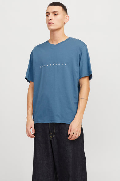 Blauw T-shirt met korte mouwen van ORIGINALS BY JACK & JONES, met witte merknaam op de borst, gedragen met een donkere denim broek.