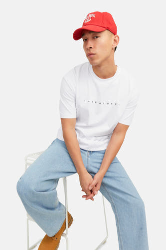 T-shirt blanc à manches courtes d'ORIGINALS BY JACK & JONES, porté avec des jeans larges et une casquette rouge.