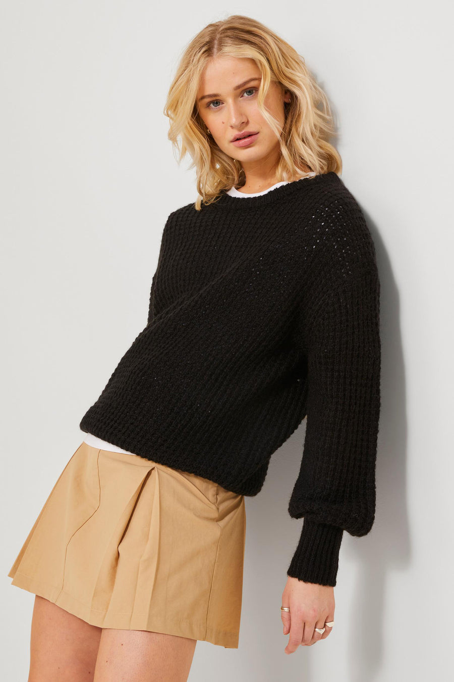 Korte beige rok van JJXX, gecombineerd met een zwarte gebreide trui en een wit shirt.
