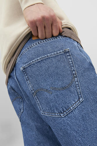 Jean bleu délavé de JACK & JONES JEANS INTELLIGENCE, avec une poche arrière et une main dans la poche.