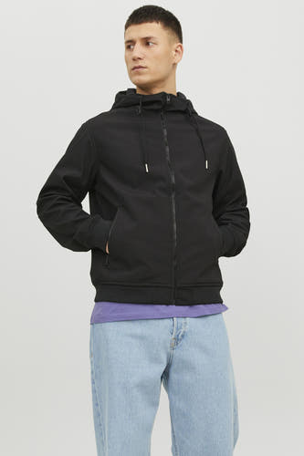 Zwarte korte jas van CORE BY JACK & JONES, met capuchon en zakken, gedragen met een paars shirt en blauwe jeans.