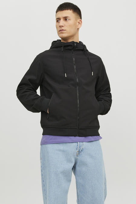Manteau court noir de CORE BY JACK & JONES, avec capuche et poches, porté avec un chemisier violet et des jeans bleus.