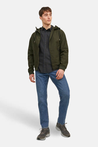 Korte groene jas van CORE BY JACK & JONES, met capuchon, gedragen over een geruit overhemd en blauwe jeans.
