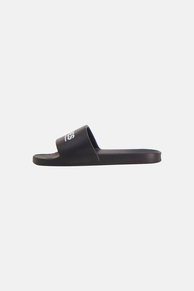 Zwarte slipper van JACK & JONES, met wit 'LES' logo op de band en 'JACK & JONES' op de zool, in zijzicht.