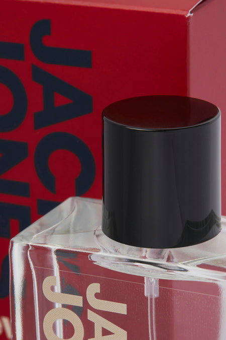 Rode parfum van ACCESSORIES BY JACK & JONES met een zwarte dop en deels zichtbare verpakking.
