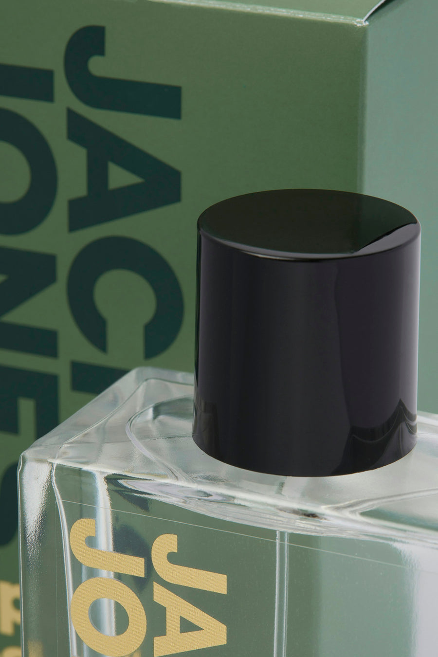 Parfum vert d'ACCESSORIES BY JACK & JONES avec bouchon noir, sur un fond vert.