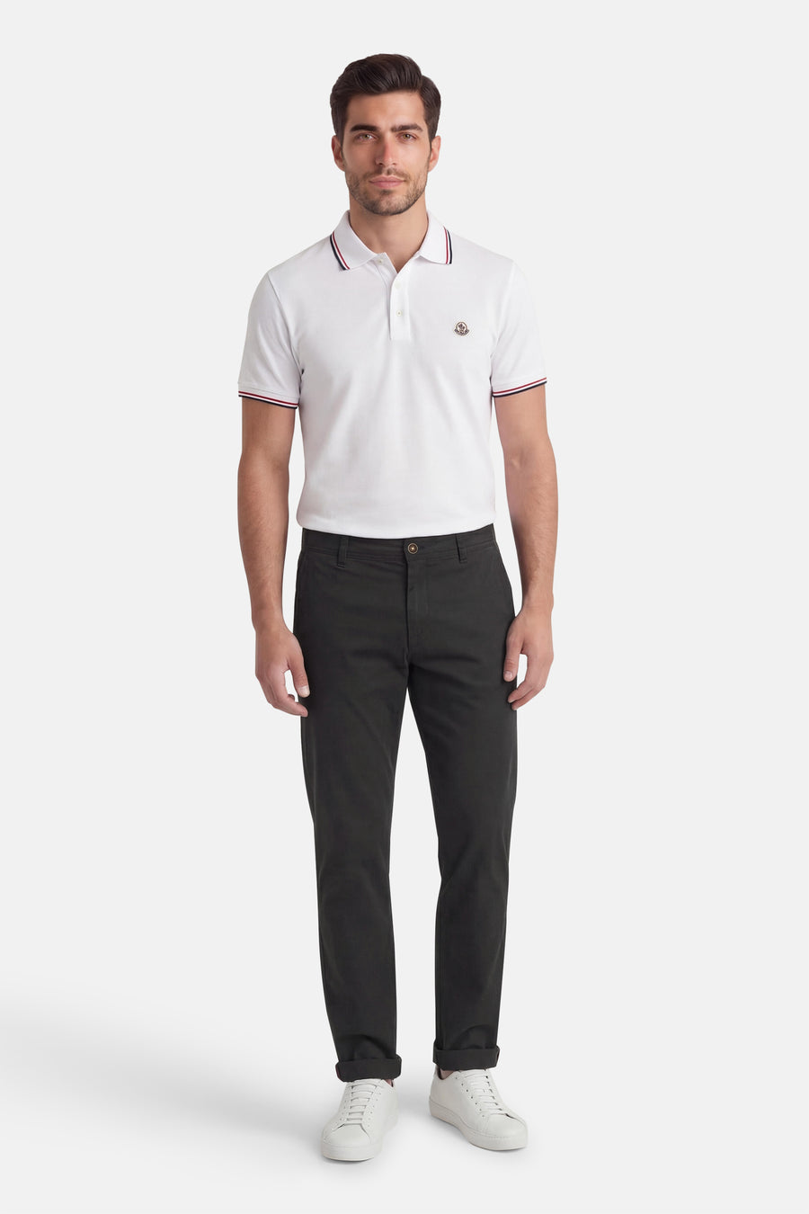 Pantalon chino noir de Jack & Jones Jeans Intelligence, avec jambes longues et ourlet retroussé, combiné avec un polo blanc et des baskets blanches.
