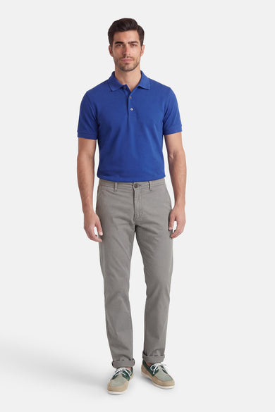 Chino gris de Jack & Jones Jeans Intelligence, avec des jambes retroussées et porté avec un polo bleu et des chaussures marron.