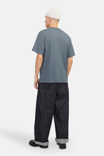 T-shirt bleu à manches courtes d'ORIGINALS BY JACK & JONES, vu de dos avec un chapeau blanc et des jeans larges.