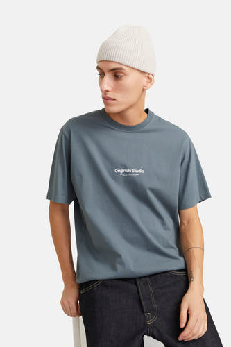T-shirt bleu à manches courtes d'ORIGINALS BY JACK & JONES, avec une impression de texte blanche sur la poitrine, associé à un bonnet tricoté et des jeans foncés.