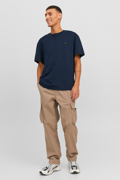 Donkerblauwe korte mouwen T-shirt van CORE BY JACK & JONES met klein logo op borst, gedragen in lifestyle shot met beige cargo broek en sneakers