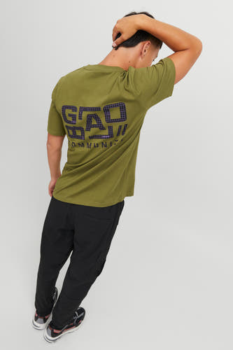 Groen T-shirt van CORE by JACK & JONES met een grafische print op de rug, gedragen met een zwarte broek en sneakers.