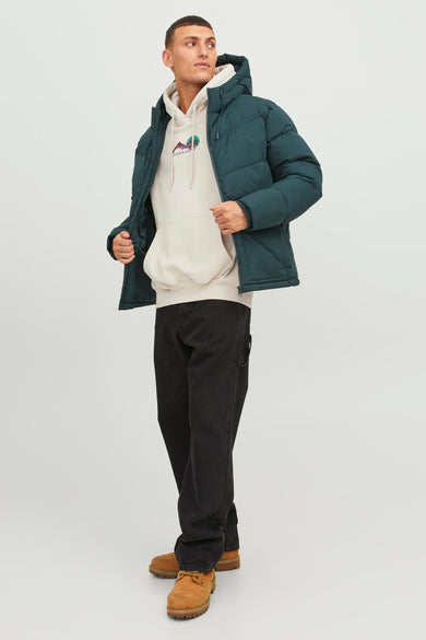 Ecru sweater met kap van ORIGINALS BY JACK & JONES, gedragen onder een groene pufferjas, gecombineerd met zwarte jeans en bruine schoenen.