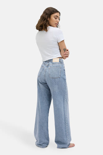 Lichtblauwe wijde jeans van JJXX, met achterzakken en een merklabel aan de tailleband, gedragen met een wit T-shirt.
