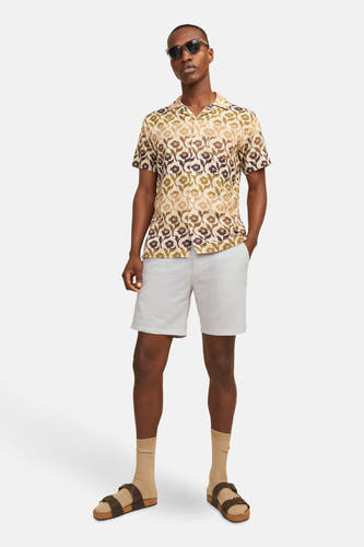 Beige short van JACK & JONES JEANS INTELLIGENCE, gecombineerd met een bloemenhemd, sokken en sandalen.
