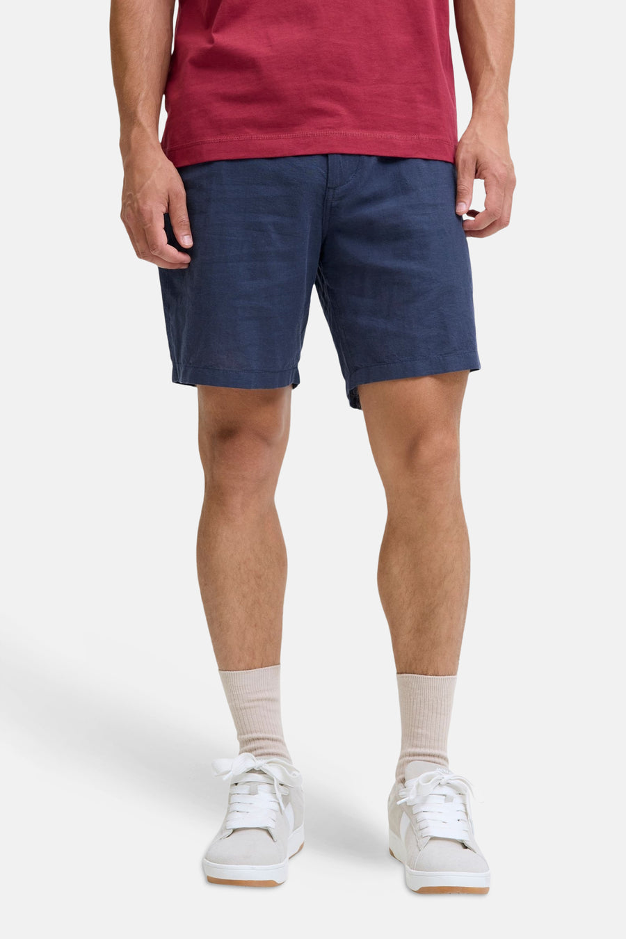 Blauwe short van JACK & JONES JEANS INTELLIGENCE, gestyled met een rood T-shirt, beige sokken en lichtgrijze sneakers.